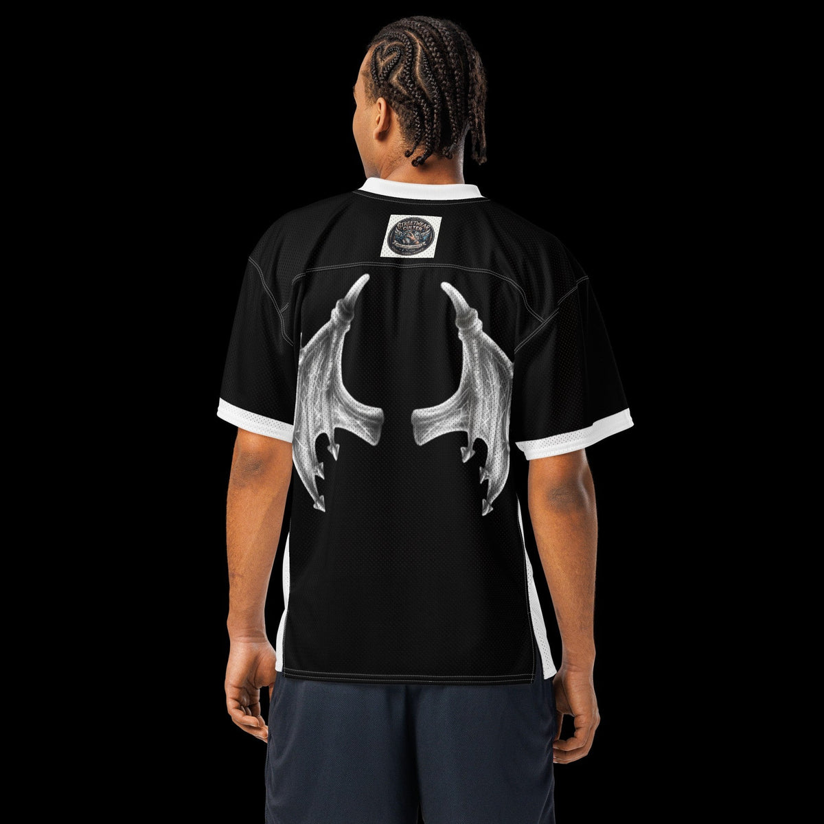 Street Culture black mesh football jersey with white wing graphic on back, worn by a man against a black background.