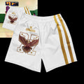 Street Culture white athletic shorts with eagle graphic, gold side stripes, and elastic waistband on stone background.